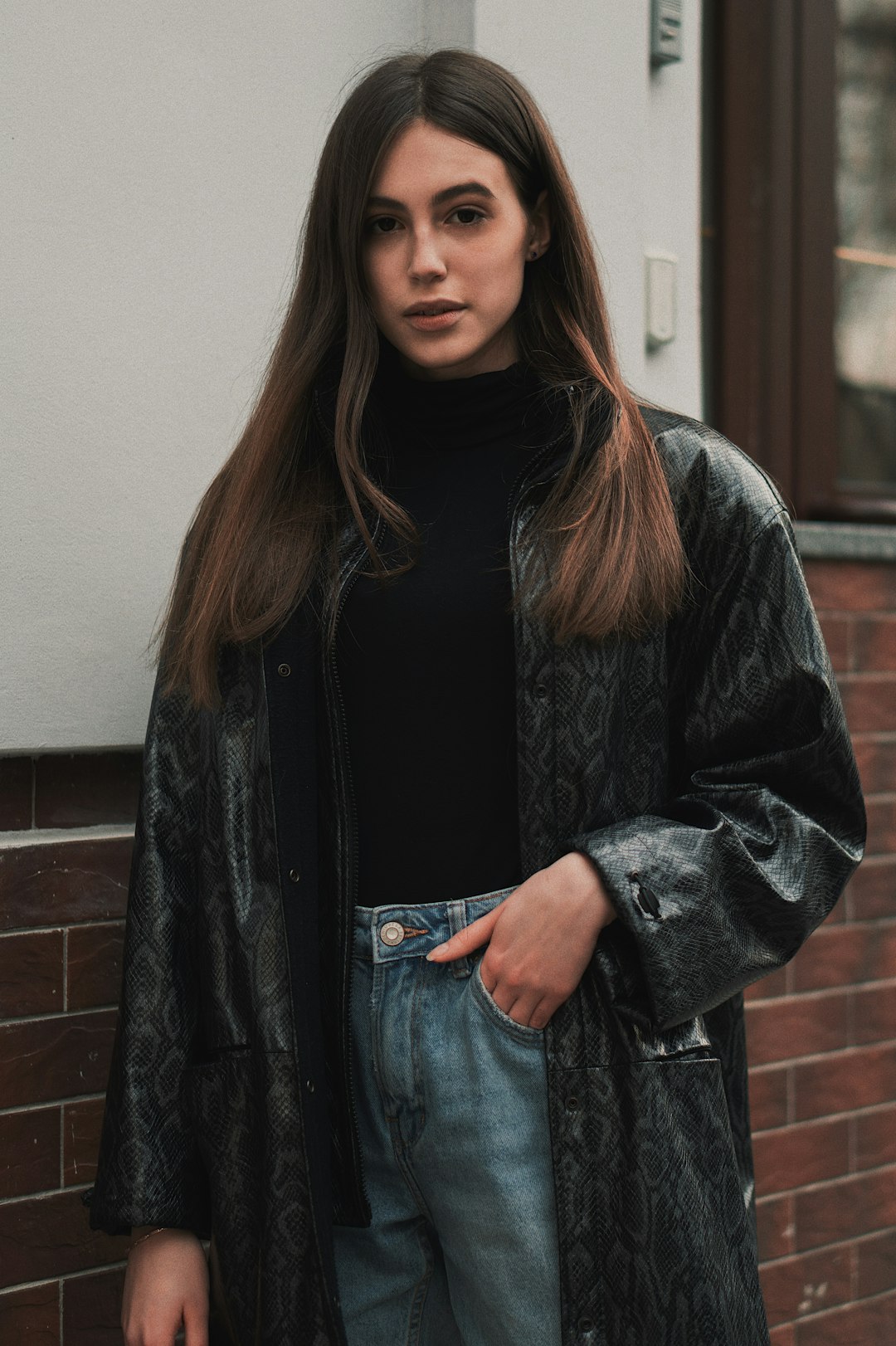 A woman in a black turtleneck and snakeskin jacket with blue jeans