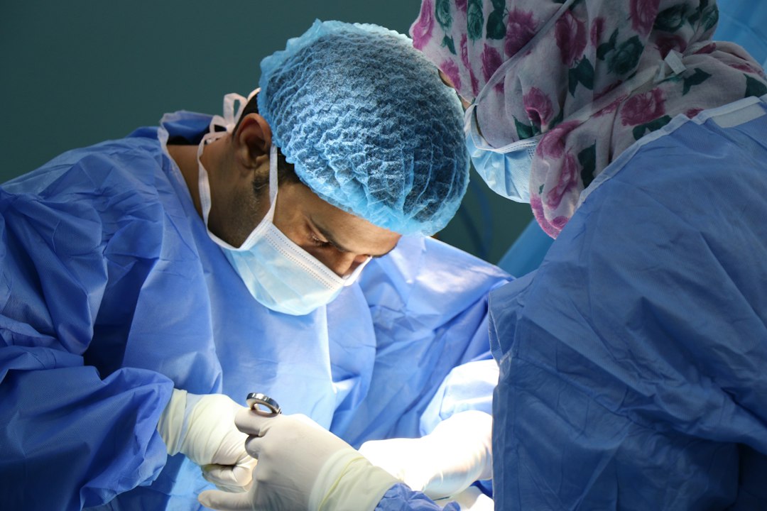Two surgeons in blue scrubs and masks performing a procedure in an operating room